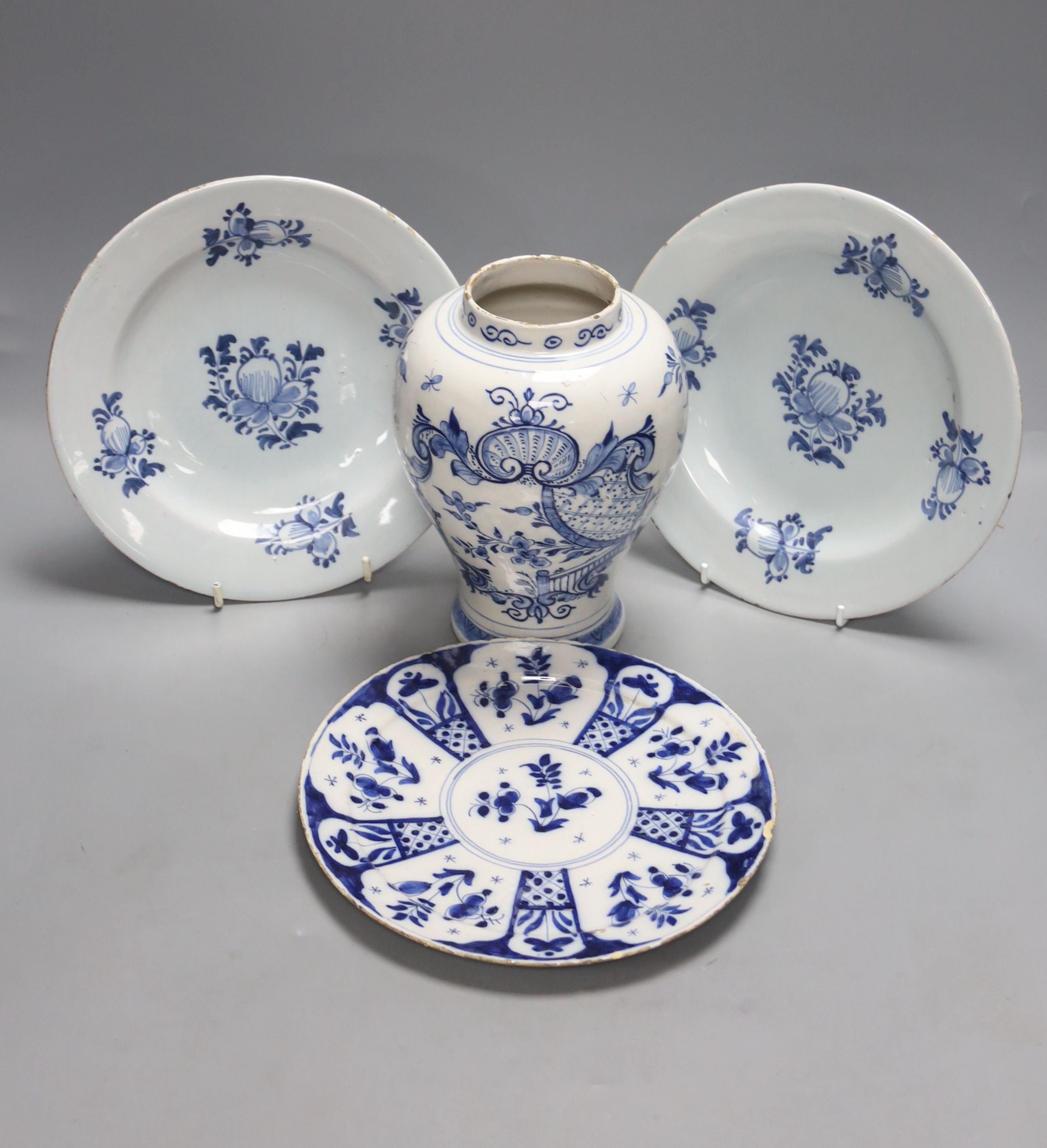 A mid-18th century Dutch Delft flower and fence-decorated blue and white baluster vase, a similar plate and a pair of English delft plates, H 20cm (vase)